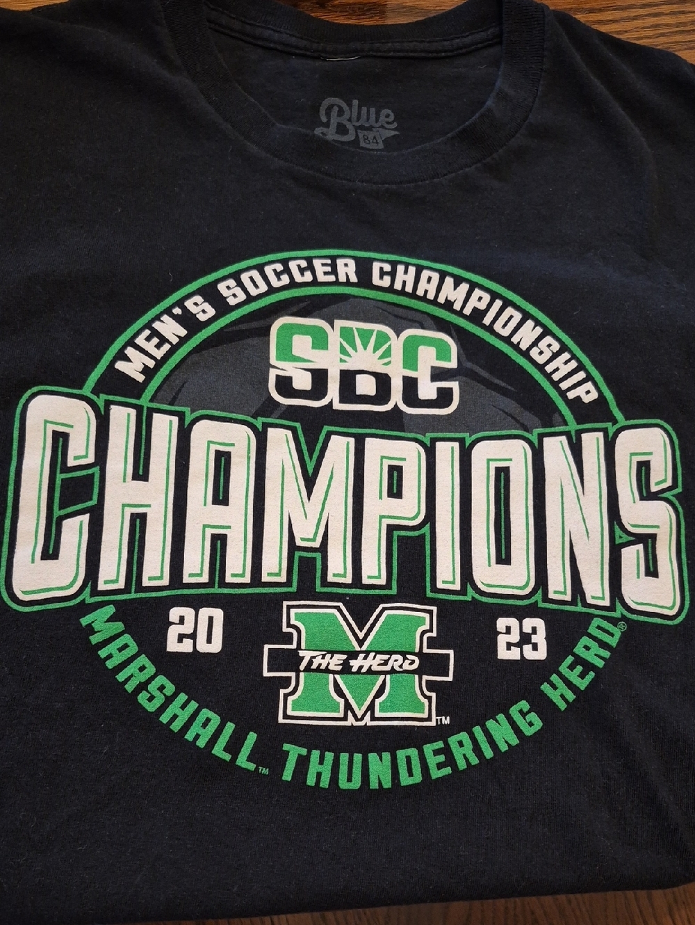 Blue 84 Men's Black T-Shirt with Green and White 'Champions' Graphic